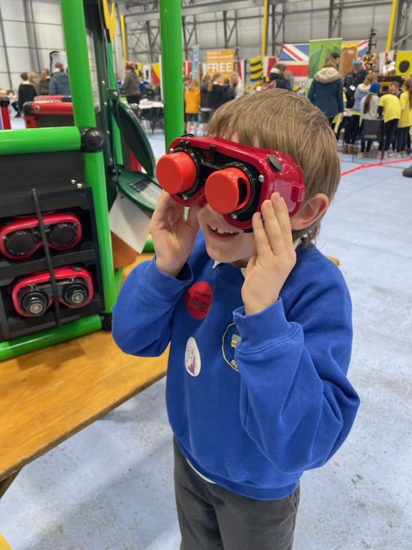 A child in a school hall looking through binoculars
